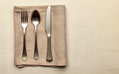 Polished metal cutlery placed on linen napkin