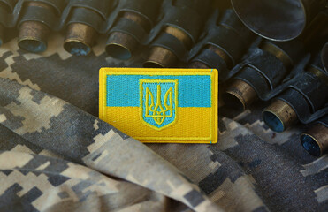 Ukrainian symbol on machine gun belt lies on ukrainian pixeled military camouflage close up