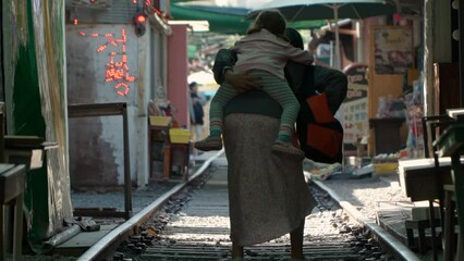 Gyeongamdong Railroad Town - Mother Carried Her Tired Daughter On Her Back While Walking On The Railroad Tracks In Gunsan, South Korea. - rear shot