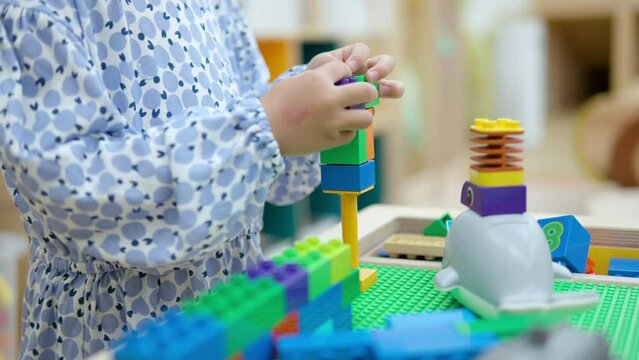 Little Girl Playing With Colorful Lego Blocks At Indoor Playroom. - close up shot
