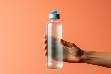 Runners hand clutching hydration water bottle isolated on a gradient background 