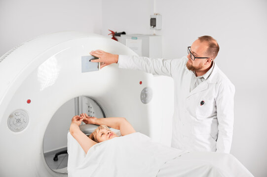 Medical computed tomography or MRI scanner. Male radiologist presses MRI button to examine female patient. Concept of healthcare and modern diagnostics.