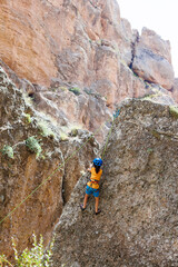 Naklejka na ściany i meble climber boy. a child in a helmet climbs a rock using equipment. children's sports.