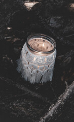 Jar with a burning candle decorated with knitted macrame fabric