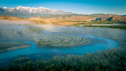Obraz premium Early morning just after sunrise. Fog in the valley of the Chuya River. Coniferous forest in the fog. Kurai steppe. Summer landscape in Altai mountains, Siberia, Russia.