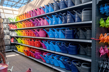 Colorful plastic watering cans on shelves in the garden center, stock photo