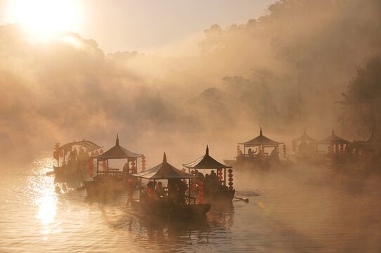 A bird's-eye view of people riding traditional Chinese boats in the morning mist at Ban Rak Thai