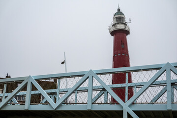 The Hague, Netherlands A red lighthouse and bridge on Scheveningen beach.