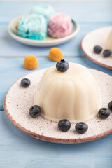 White milk jelly with blueberry on blue wooden,  side view, selective focus.