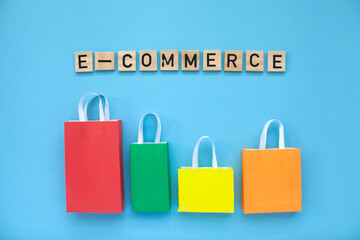 E-commerce and online shopping concept. Colourful bags and  wooden letters on the blue background. Top view.