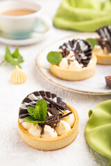 Sweet tartlets with chocolate and cheese cream with cup of coffee on a gray concrete background. side view, selective focus.