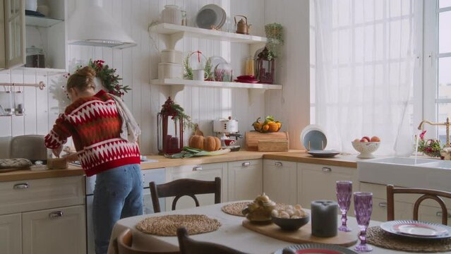 Busy and energetic young woman in a rush cooking dinner and hustling in the kitchen. Multitasking dinner preparation. housewife mom serves table, washes vegetables, cuts bread