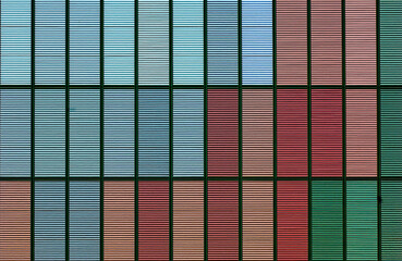 Geschlossene Jalousien an einer Hochhausfassade in verschiedenen, dezenten Farben