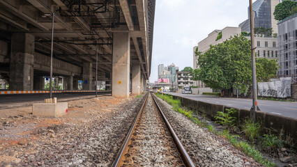 Fototapeta na wymiar A railroad track with steel on both sides to allow trains to run. The floor is full of stones. On the side is a road and condos.