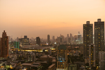 A modern city skyline captured at sunset, with high-rise buildings illuminated by the golden glow of evening light.