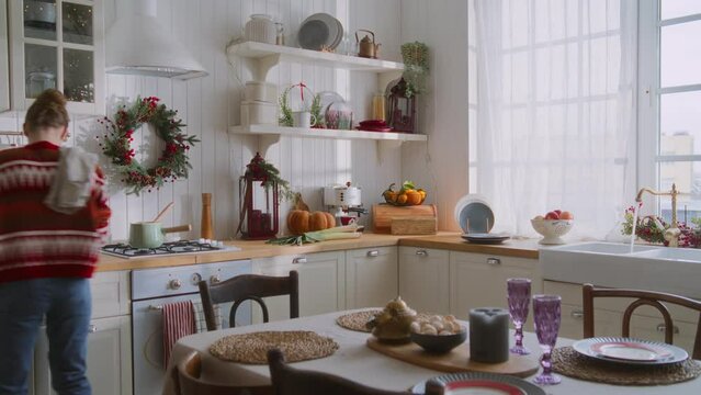 Busy and energetic young woman in a rush cooking dinner and hustling in the kitchen. Multitasking dinner preparation. housewife mom serves table, washes vegetables, cuts bread