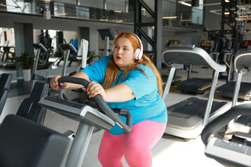 Fototapeta premium Tired young woman with obesity on treadmill during training workout