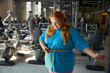 Obraz premium Happy satisfied overweight woman seeing good result on measuring tape