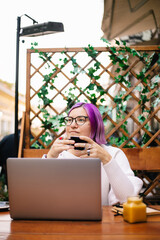 A woman drinking coffee in a cafe 
Portrait of a beautiful girl with purple bob hair sitting in a cafe, drinking coffee