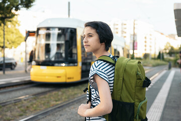 Teenage student girl waiting for the streetcar at the station  to go to school
