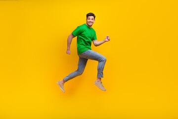 Fototapeta na wymiar Full size photo of positive cheerful guy wear stylish t-shirt jumping run shopping to empty space isolated on yellow color background