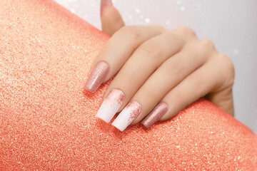 Female hand with long nails with glitter nail polish. Long orange nail design. Women hand with...