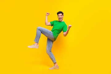 Fototapeta na wymiar Full size photo of overjoyed guy wear stylish t-shirt clenching fists shooting yes win lottery isolated on yellow color background