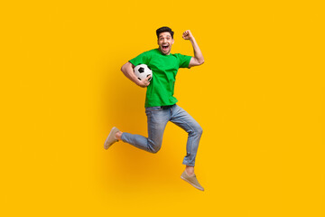 Fototapeta na wymiar Full size photo of crazy guy wear stylish t-shirt jeans run with football ball in hand support team isolated on yellow color background