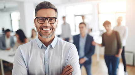 Confident businessman with glasses smiling, team working in background