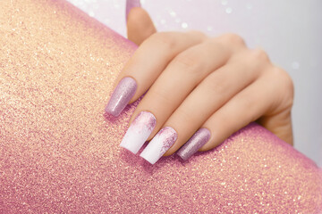 Female hand with long nails with glitter nail polish. Long pink nail design. Women hand with sparkle manicure on glitter background