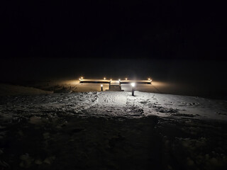 Night view of the pier in winter on the lake illuminated by lamps, beautiful view, snow on the lake