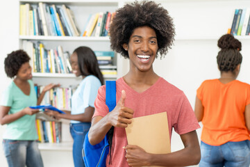 Group of african american students at library with successful black male student in front