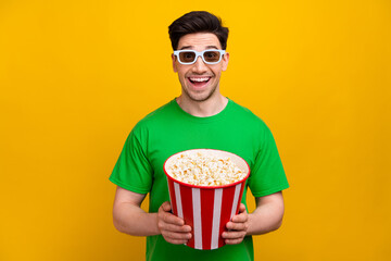 Portrait of astonished guy with brunet hairstyle wear stylish t-shirt in 3d glasses hold pop corn...