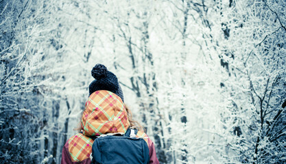 woman with hat walking in frost covered forest in winter