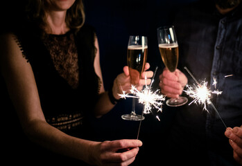 couple holding sparkles and champagne glasses Happy New Year