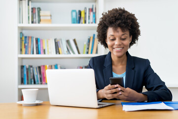 African american business trainee sending message with mobile phone