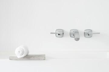 ceramic washstand sink with grey metal faucet water-tap and white towel on raw concrete cement stone indoor clean clear neat bathroom wall background lifestyle