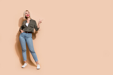 Full body length photo of confident promoter girl directing finger empty blank space isolated beige color background