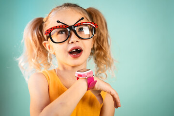 Technology for children: a girl wearing funny glasses uses a smartwatch. Portrait.