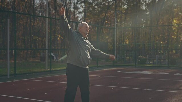 A retired man on the sports field in the park doing exercises. Keeping healthy in old age