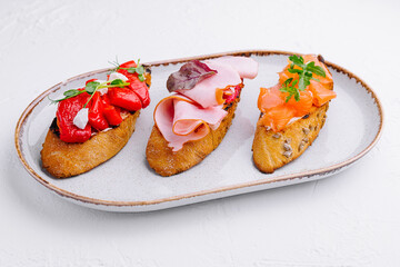various bruschettas with ham, pepper and salmon