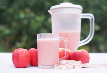 Pink apple fruits smoothie in glass and blender, outdoor background.Concept, healthy beverage for health. Well being and weight loss menu. Homemade refreshing fruit drinks. High fibers, detox.  