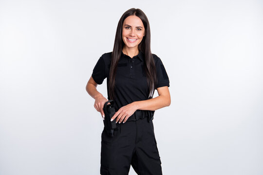 Photo of cheerful positive young policewoman dressed black clothes arm gun smiling isolated white color background