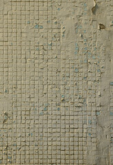 The texture of the old concrete wall, with a coating of shallow tiles of square shape, painted in gray. Background image of a wall of many square white tiles