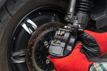 the master removes the brake caliper of an electric motorcycle, the concept of seasonal maintenance...