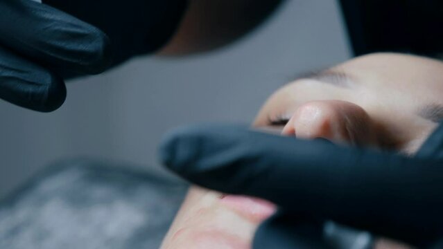 lip augmentation procedure. close-up, female lips. Male surgeon injectionist carefully and slowly injects hyaluronic acid into woman's lips with a syringe. beauty injections. Plastic surgery.