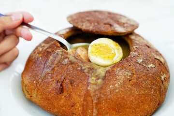 Indulge in the authentic flavors of Polish cuisine with a delectable soup served in a freshly baked bread loaf, a traditional and iconic national dish.