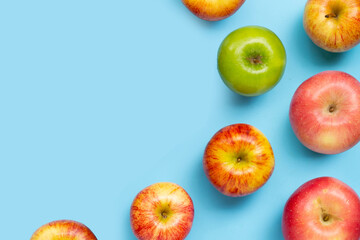 Variety of fresh apples on blue background.