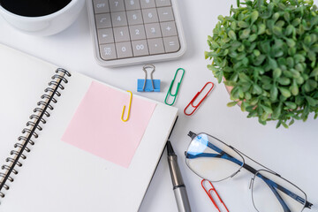 Office desk with pink sticker on notebook. - obrazy, fototapety, plakaty