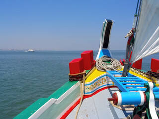 View from the Tagus river estuary from the prow or bow of the sailboat Amoroso, a historical, typical or traditional Varino type Tagus river estuary boat with Lisbon in the horizon
